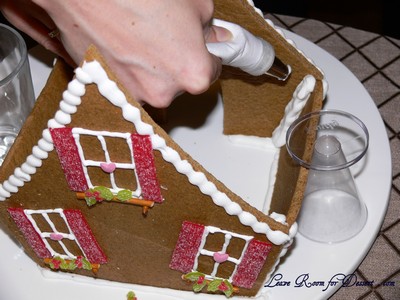 Pipe royal icing on the plate and the sides of the wall before placing walls in place. Pipe extra royal icing in the inside of the house. Make sure the walls are stable before attempting to put the roof on.